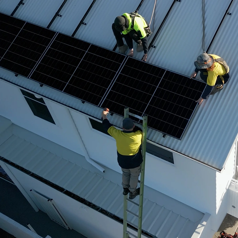 Installers mounting solar panels on roof railings